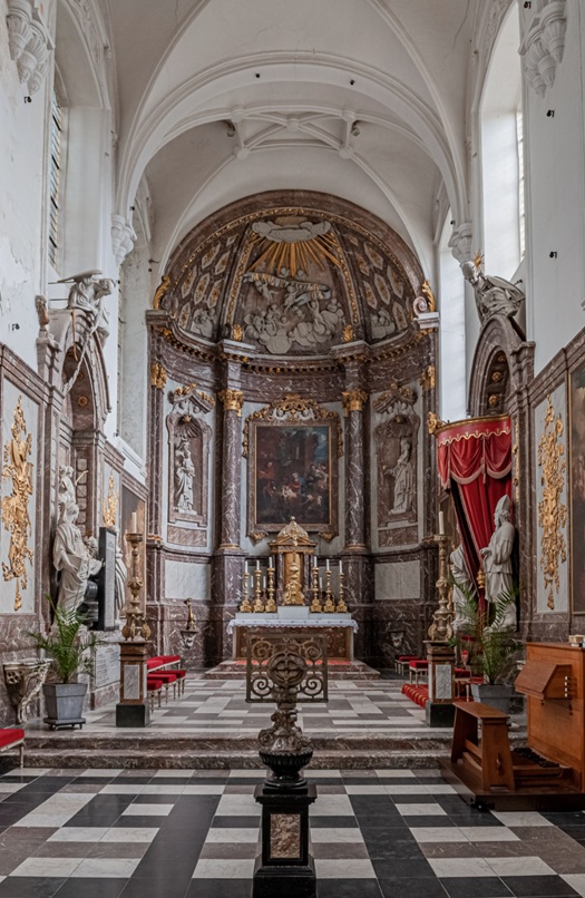 Interieur van een katholieke kapel met altaar, marmeren zuilen, rode gordijnen en zwart-witte tegelvloer.
