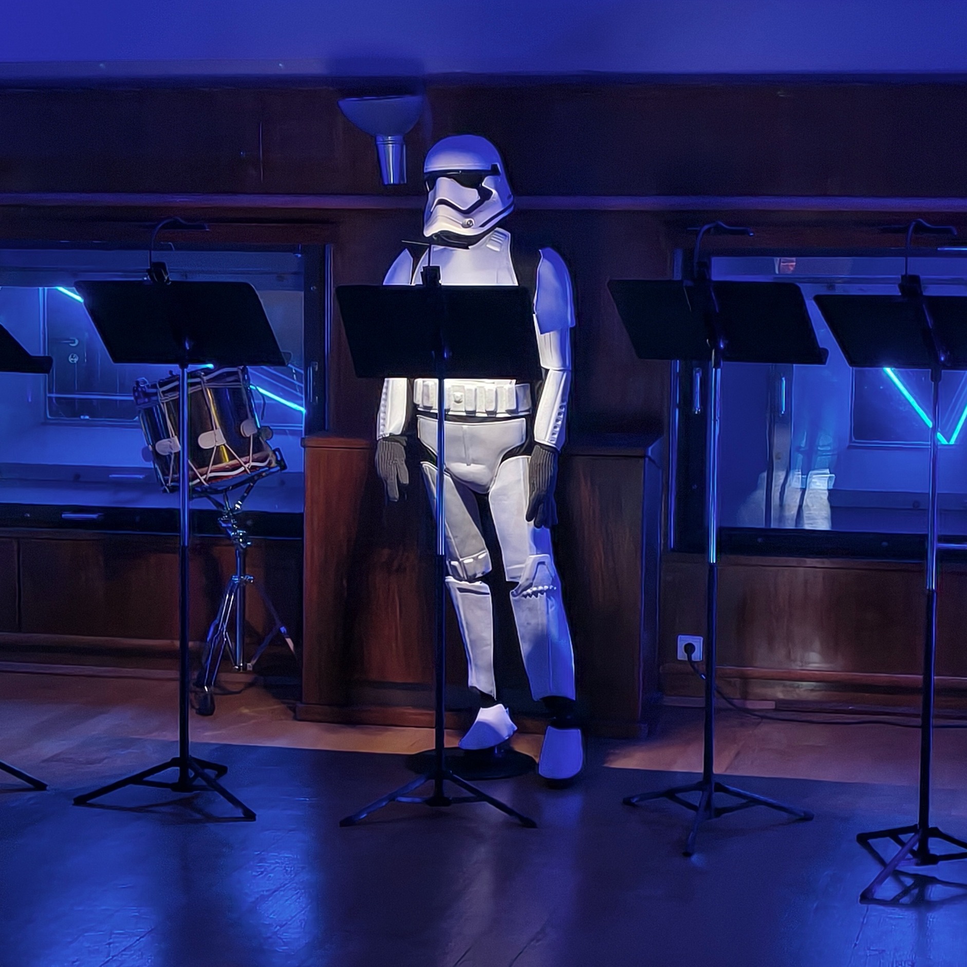 Grote witte stormtrooperfiguur staat in studio met blauwe verlichting en statieven op de achtergrond.